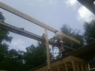 Carpenter setting a ridge beam over a new addition frame — Ice Dam Removal by Roofing Brothers in Winston