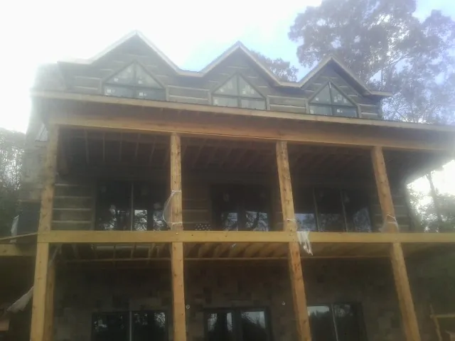 Dormers and porch framing on a large log home under construction — Roof Coating work by our crew in Winston