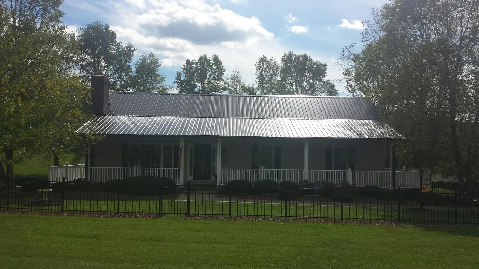 Gray metal roof on a brick ranch with a full width front porch — Gutter Guard Installation work by our crew in Winston