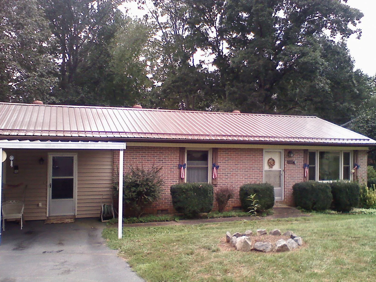 Bronze metal roof and carport on a brick ranch home — Roof Repair work by our crew in Winston
